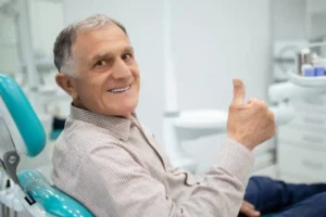 Person approaching age 65 giving a thumbs up during a routine appointment
